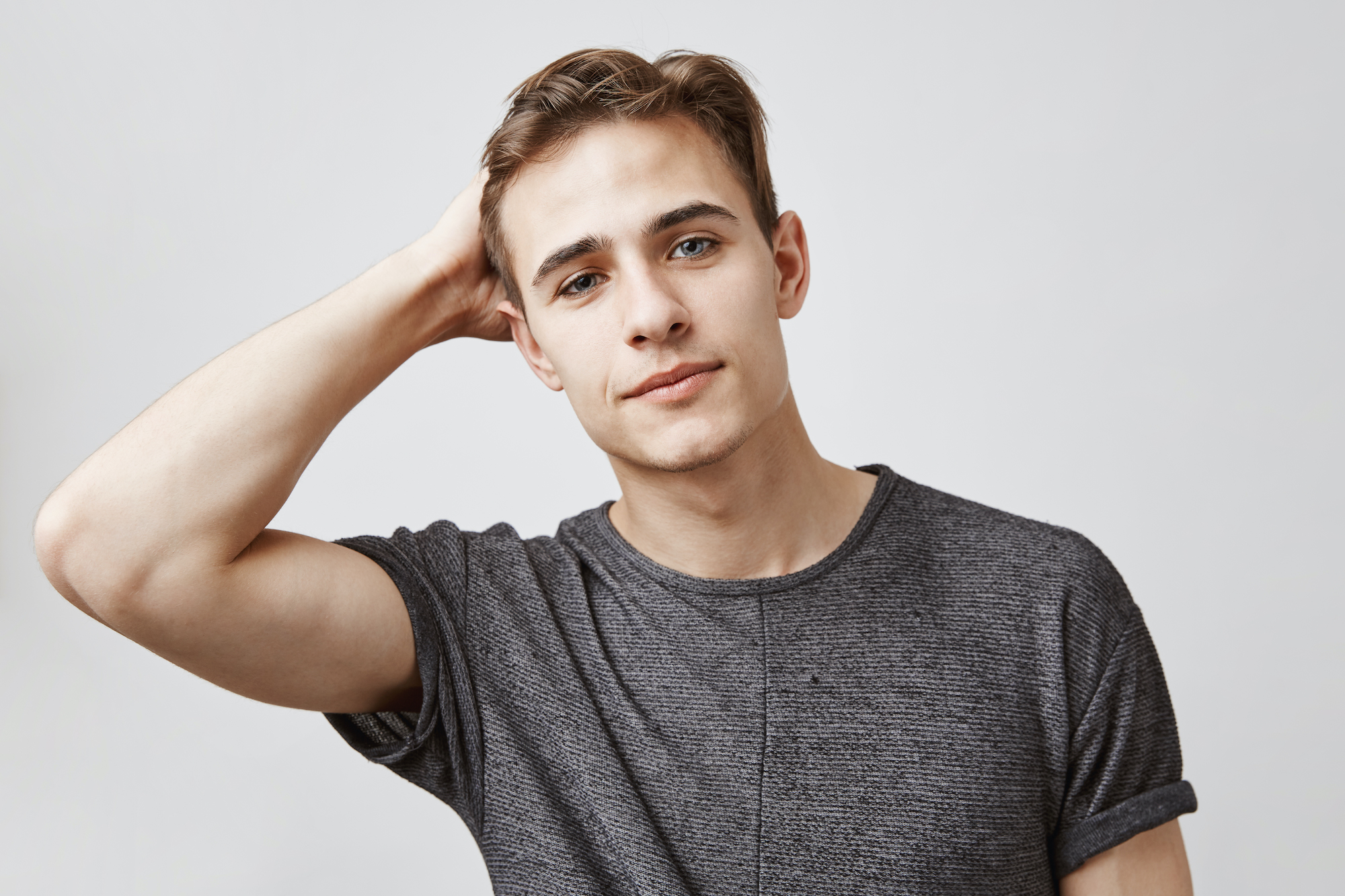Portrait of young attractive man touching his hair. How do you like my new haircut. My friend gets married and I am invited. Need to look stylish, maybe I will find someone single.